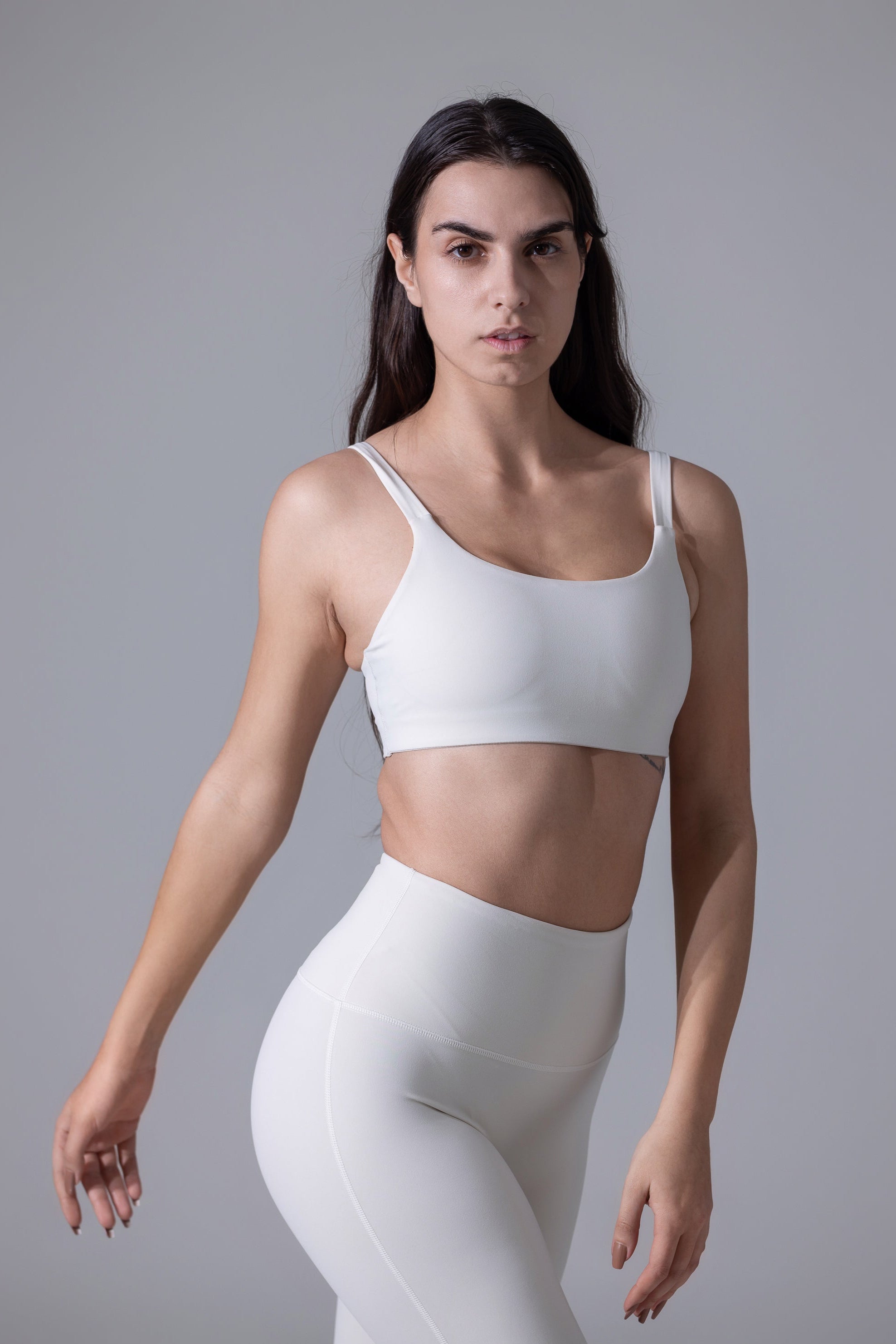 A woman wearing a white sports bra with adjustable straps and a mesh design.