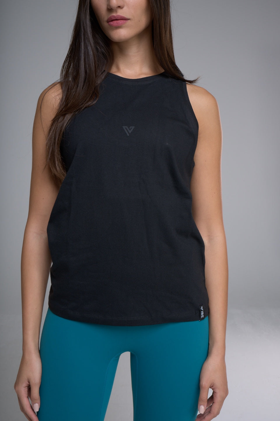 A female model wearing a black tank top with a round neckline and short sleeves.