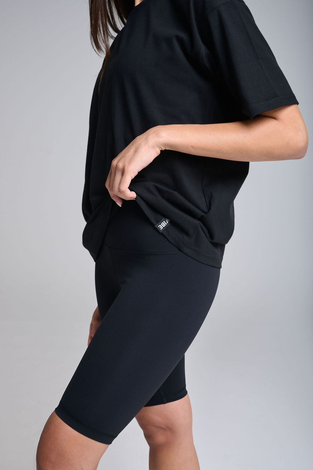 A pair of black biker shorts, form-fitting and high-waisted, displayed on a model who is posing with one hand on her hip.