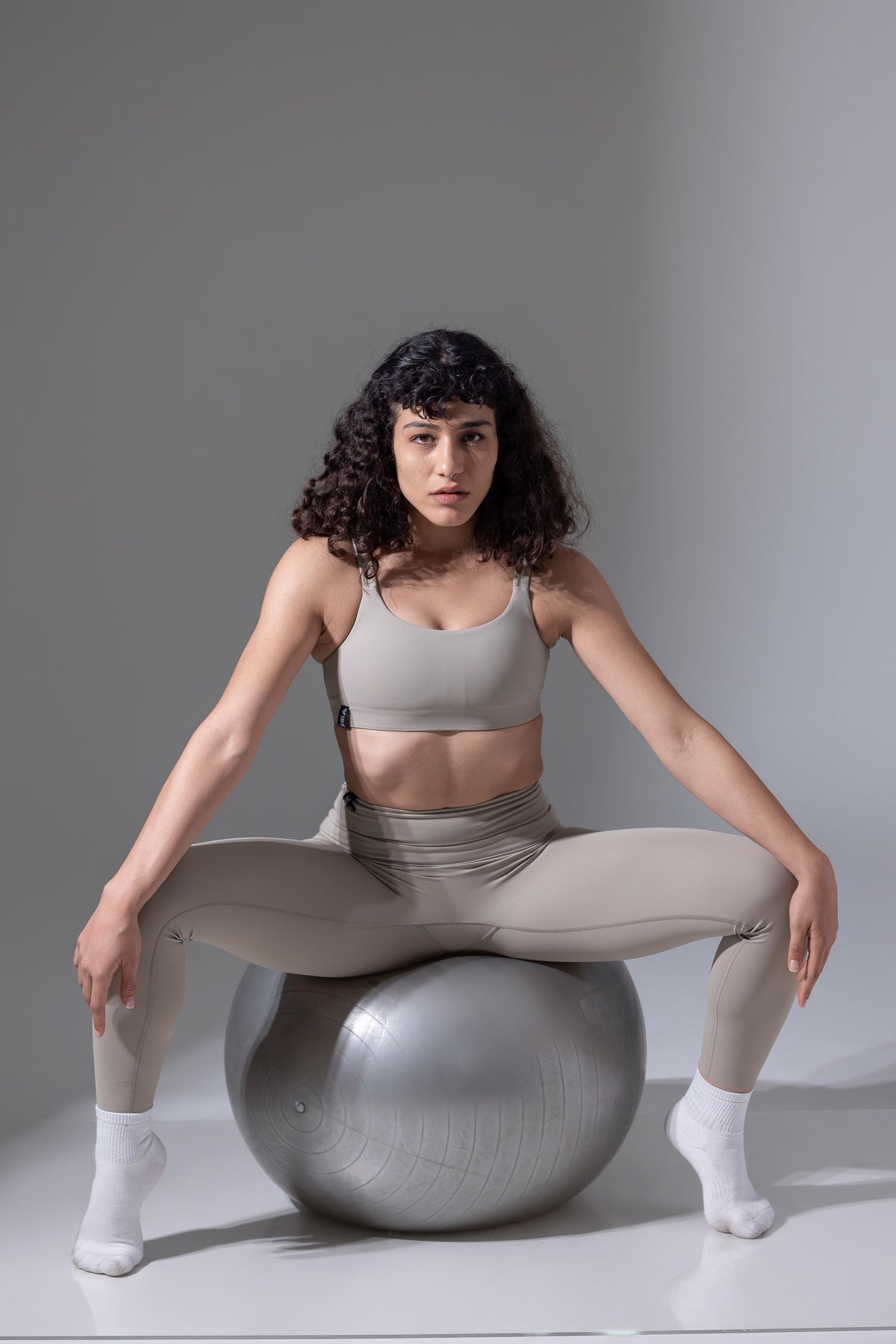 Woman sitting on a large exercise ball against a plain background