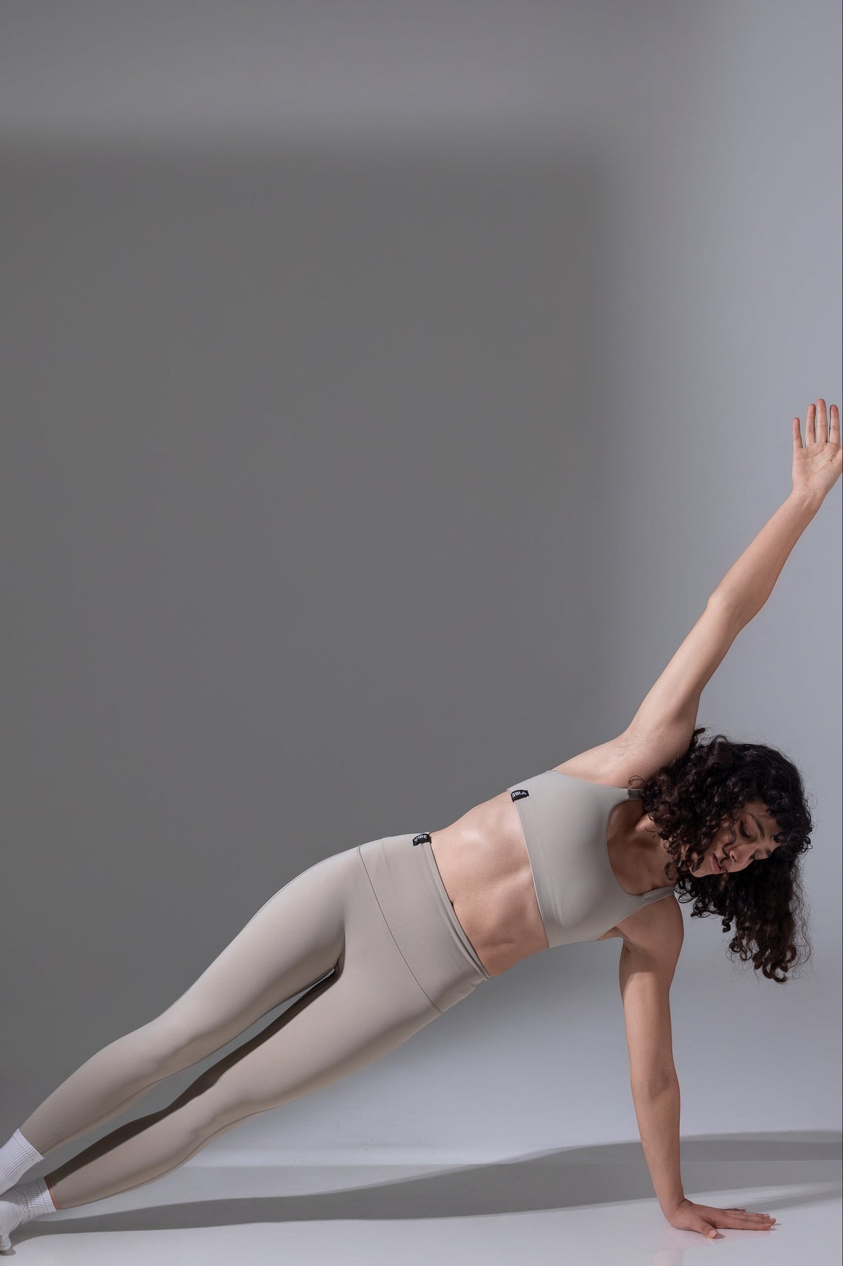 Woman in a yoga pose on a gray background