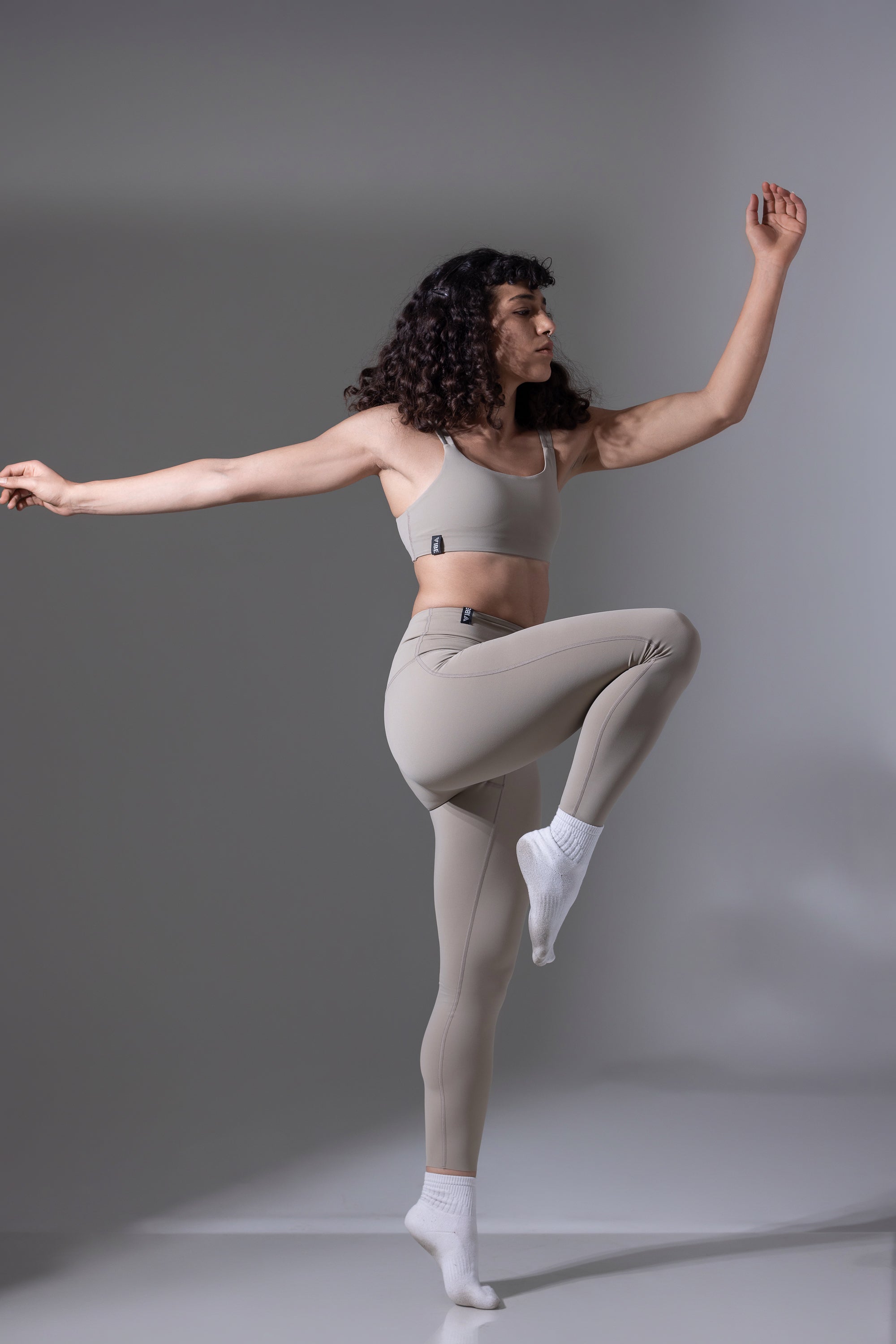 Woman in athletic wear posing against a gray background